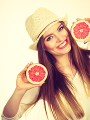 Woman holds two halfs of grapefruit citrus fruit in hands