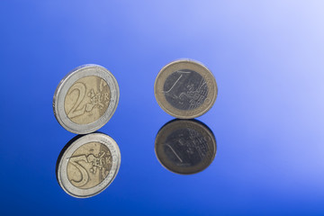 Closeup of two and one Euro coins on blue background with nice reflection