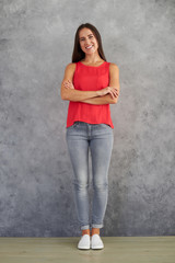 Wall Mural - Young female in stylish casual wear standing against gray backgr