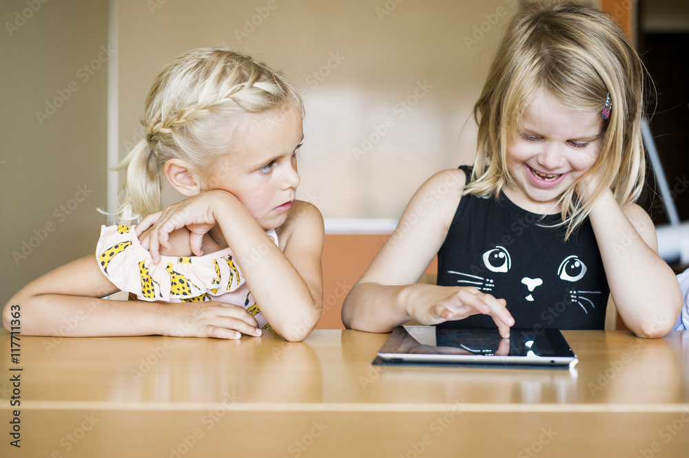 Two girls using digital tablet at table Stock Photo | Adobe Stock