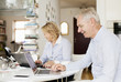© Astrakan Images - Happy senior business couple using laptops at home