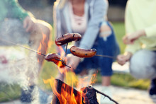 Group Of Friends Preparing Sausages On Campfire