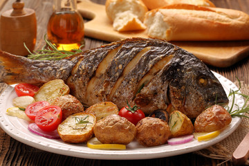 Grilled fish with roasted potatoes and vegetables on the plate