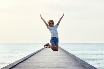 Wall Mural - Happy jumping girl on the pier