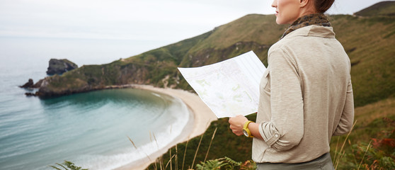 woman hiker with map in front of ocean view landscape