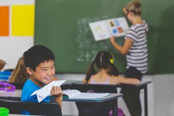 Poster - Boy with a paper plane while teacher teaching in classroom