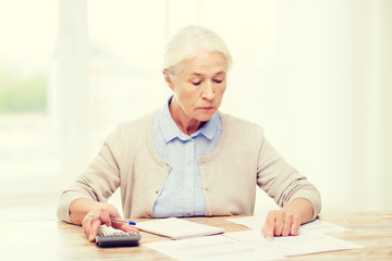 Poster - senior woman with papers and calculator at home