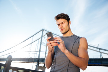 Poster - Runner using mobile smart phone and standing at the bridge