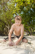 © travelview - happy young boy is digging in the sand of the beach