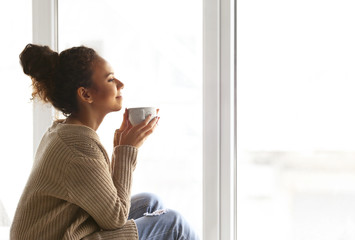 Beautiful African American girl drinking coffee at home