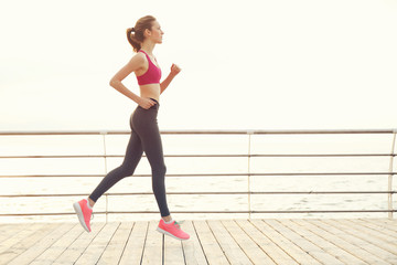 Wall Mural - Young woman running on pier