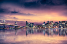 San Francisco California skyline with lights and bay under colorful sunset sky
