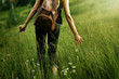woman traveler walking among grass in meadow and holding in hand
