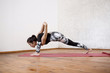 © Cookie Studio - Young beautiful athletic girl practicing indoor yoga streching asana on red mat.