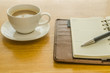brown leather organizer with pen and coffee