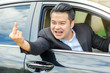 Asian young man driving a car and showing the middle finger