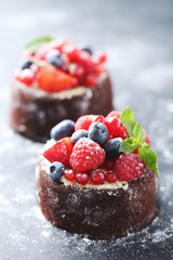 Wall Mural - Sweet chocolate cakes with berries on black wooden table