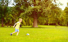 Sporting Boy Plays Football In Sunny Park