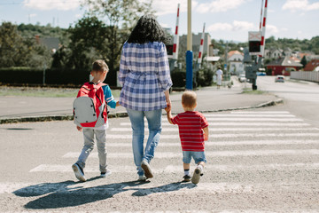 back to school. mother with children crossing road on way to school.