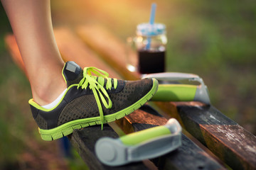 Woman raised her leg on the bench, after training in nature