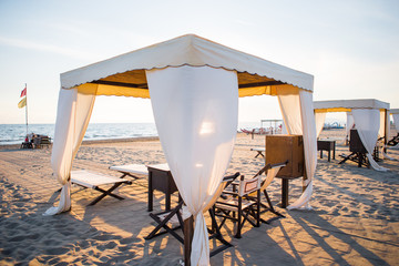 Wall Mural - Wooden sunbeds in front of a turquoise sea in the evening light. Sunbeds in famous italian sand beach at Forte dei Marmi