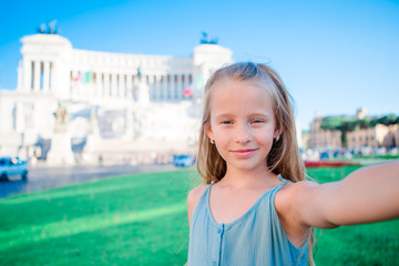 Adorable little girl taking selfie in front of Altare della Patria, Monumento Nazionale a Vittorio Emanuele II also known as II Vittoriano, Rome, Italy.