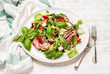 Summer arugula, prosciutto and strawberry salad over white painted wooden background, selective focus