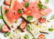 Summer watermelon, strawberry and feta cheese salad with wint leaves and pistachios on white plate, top view, horizontal composition
