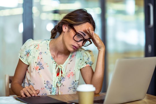 Frustrated female graphic designer looking at laptop