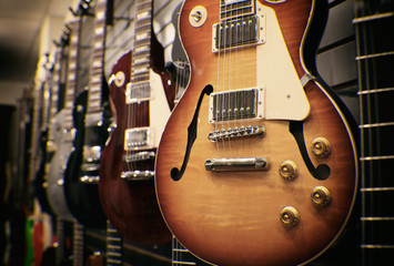 row of guitars on display for sale hanging in a music store - vintage instagram filtered.