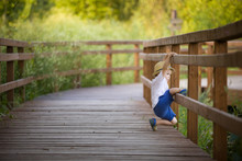 Cute Little Toddler Boy In Straw Hat Playing On The Countryside Wooden Bridge On A Sunny Summer Day. Lifestyle Concept