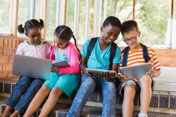 Poster - Kids sitting on staircase using laptop and digital tablet 