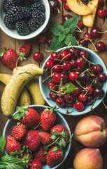 Wall Mural - Summer fresh fruit and berry variety over wooden backdrop, top view, vertical