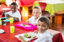 Children Having Lunch During Break Time In School Cafeteria
