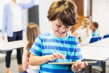 Poster - Smiling schoolboy using digital tablet in classroom