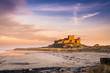 Golden Bamburgh Castle, on the Northumberland coastline, bathed in late afternoon golden sunlight