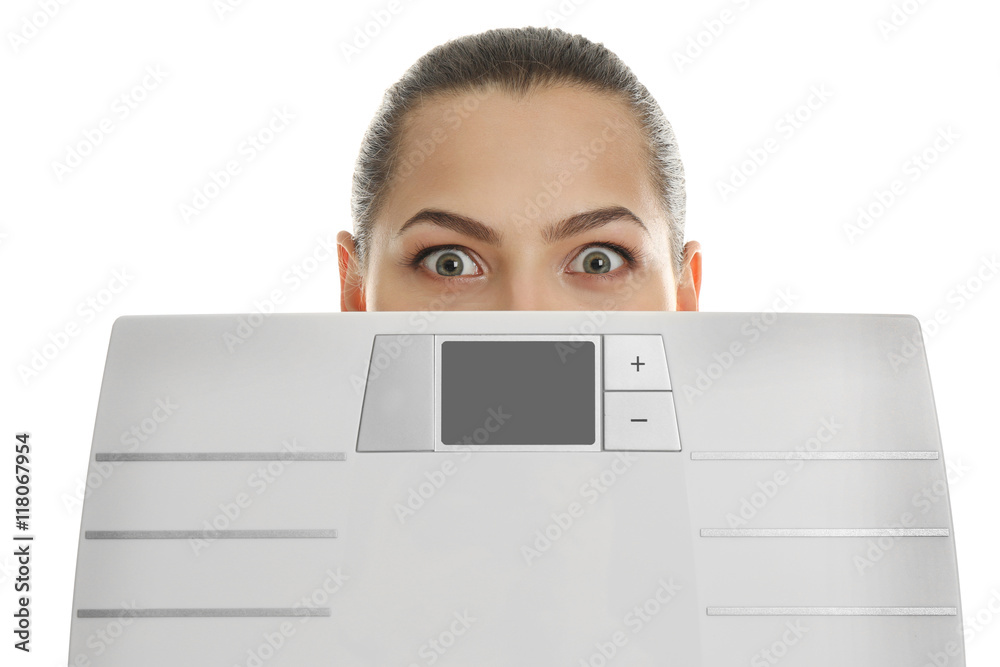 Beautiful young woman hiding behind scales on white background