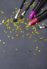 Wall Mural - Make up products with glitter stars on a rustic slate background forming a page border