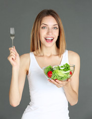 Wall Mural - Woman holding a bowl of salad on color background