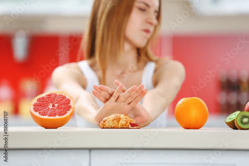 Fotografija Woman refuse eating croissant lying among fruits