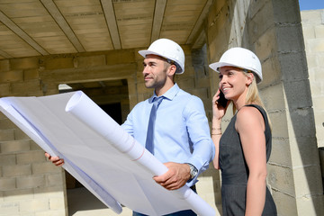 Wall Mural - cute young woman architect with handsome foreman in building industry construction site