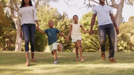 Poster - Low angle view of happy family holding hands and walking