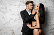Handsome man in black suit touching sexy woman in lingerie
