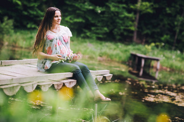 Young beautiful pregnant woman relaxing at the lake. Pregnacy with baloons on pier