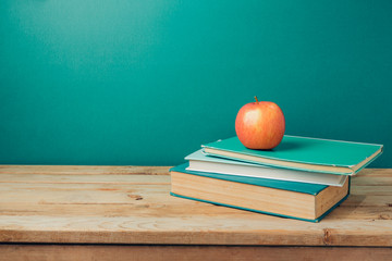 Back to school concept with books and apple on wooden table over green background