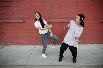 Wall Mural - Young Asian woman in city dancing hip hop