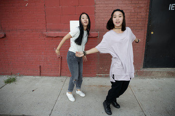 Wall Mural - Young Asian woman in city dancing hip hop