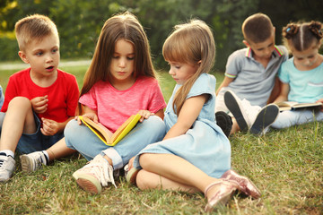 Wall Mural - Group of happy kids reading books in park