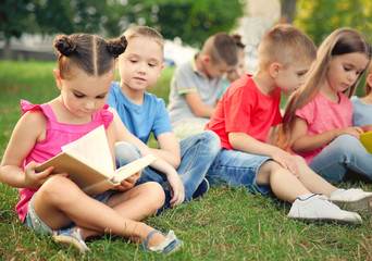 Wall Mural - Group of happy kids reading books in park