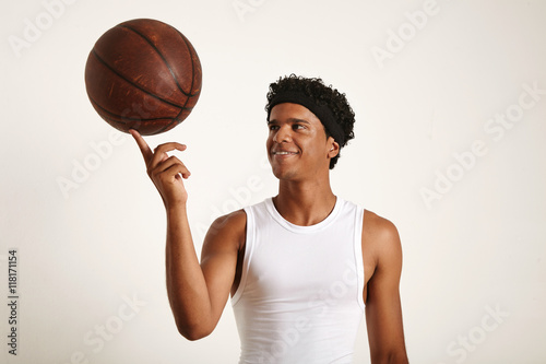 Closeup Shot Of A Playful Smiling Young Attractive African American Basketball Player Wearing A White Sleeveless Shirt Holding An Old Leather Ball On One Finger Isolated On White Buy This Stock Closeup Shot Of A Playful Smiling Young Attractive African American Basketball Player Wearing A White Sleeveless Shirt Holding An Old Leather Ball On One Finger Isolated On White Buy This Stock